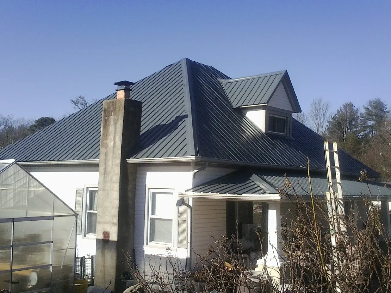 Dark blue standing seam metal roof on a white farmhouse with dormer — Slate & Tile Roof Repair by Roofing Brothers in Chesnee