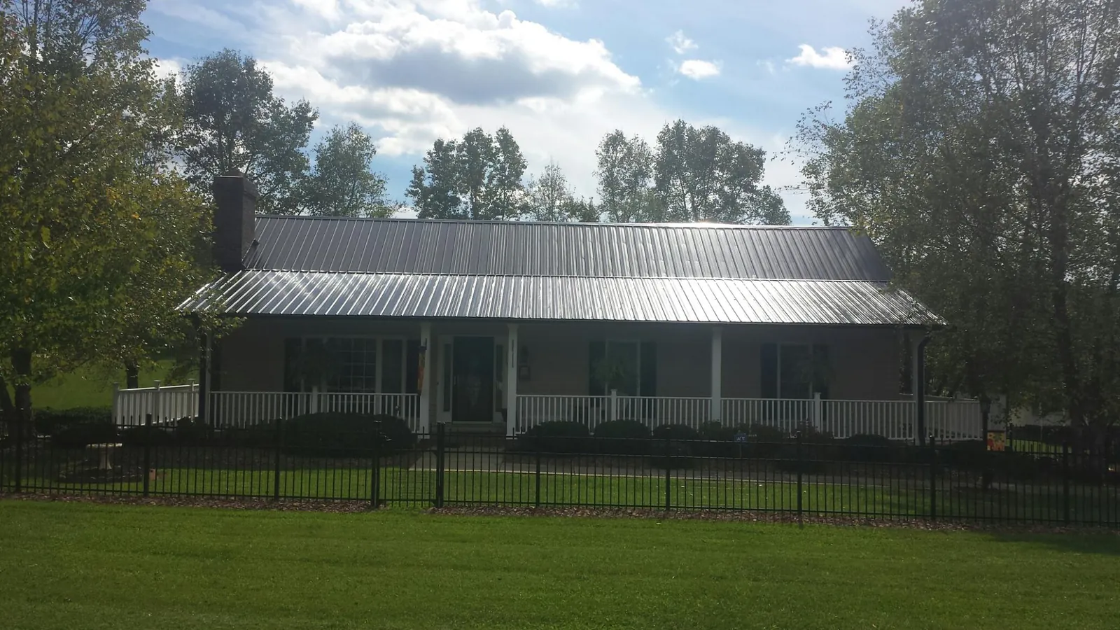 Gray metal roof on a brick ranch with a full width front porch — Gutter Guard Installation work by our crew in Chesnee