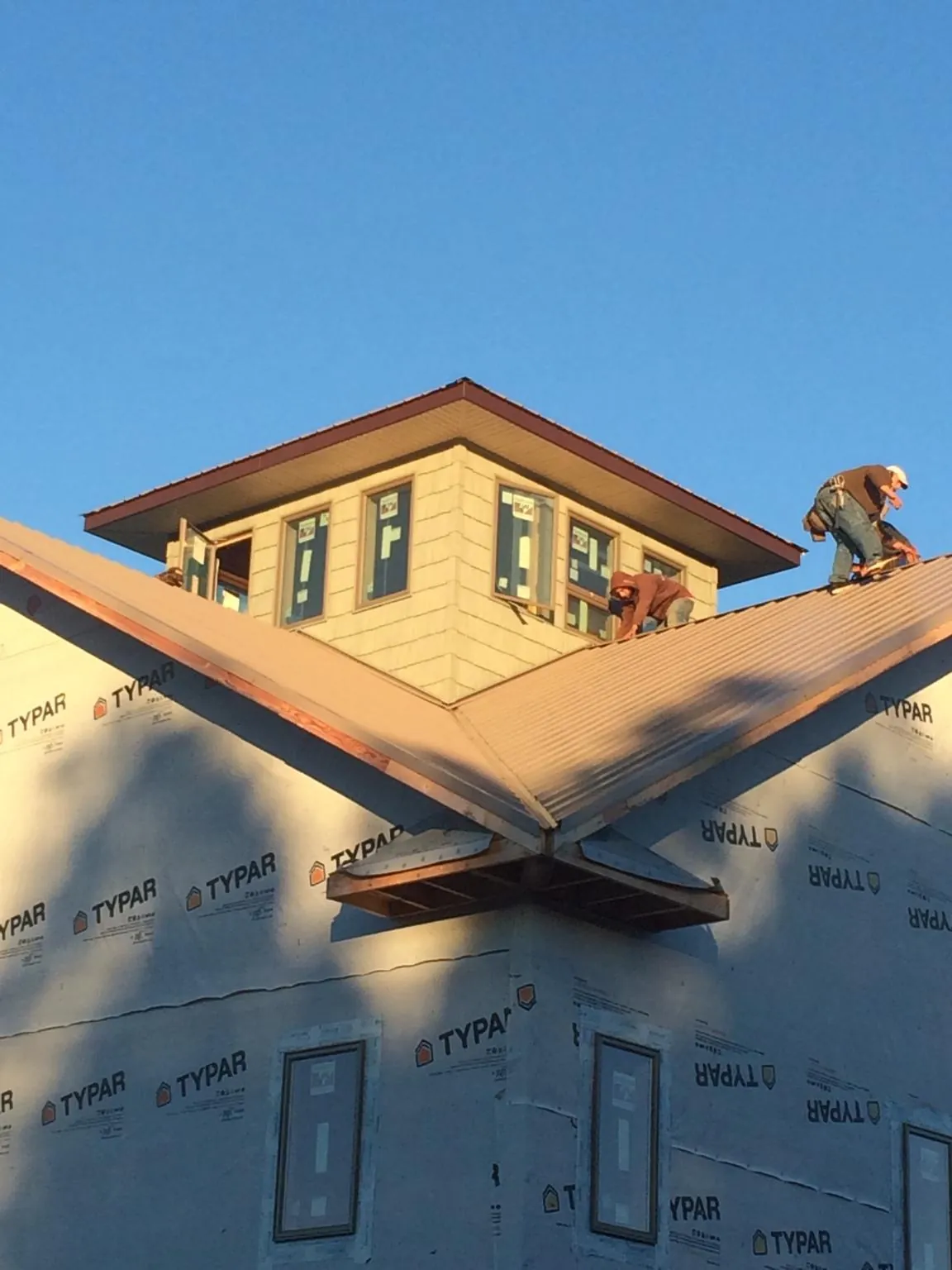 Roofers working around a rooftop cupola on a new metal roof at sunset — Roof Waterproofing in Chesnee by Roofing Brothers